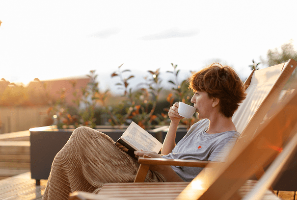 Woman reading and drinking coffee outdoors